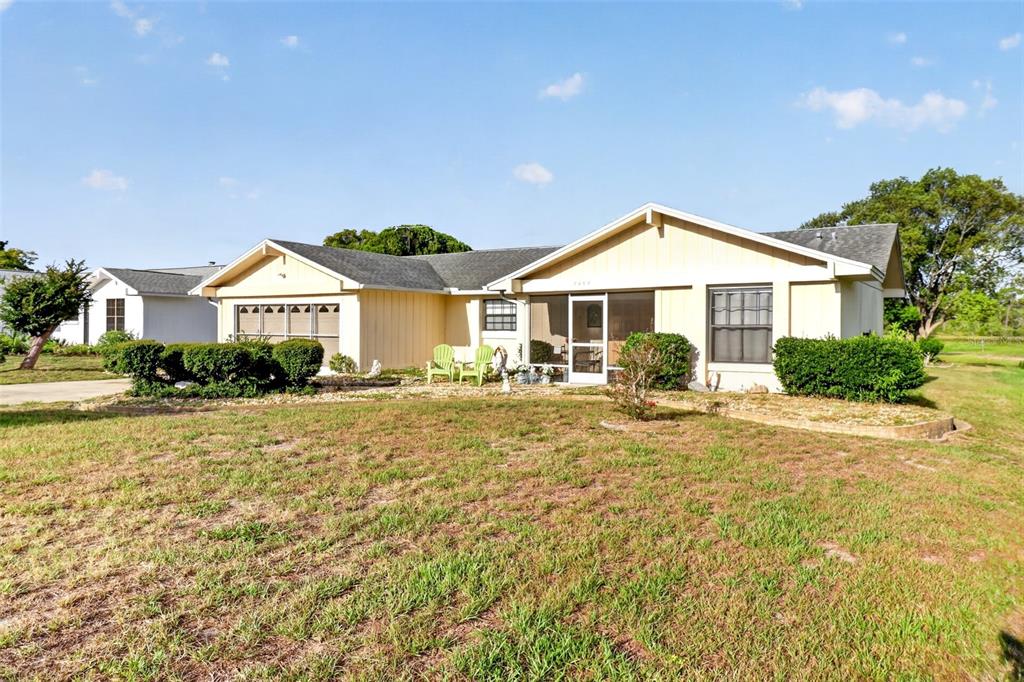 A single-story house with light yellow siding, a screened porch, and a grassy front yard — 7465 GALLOWAY ROAD, WEEKI WACHEE, FL