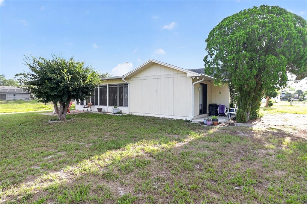 The exterior of a single-story house features a screened-in porch and two large trees — 7465 GALLOWAY ROAD, WEEKI WACHEE, FL
