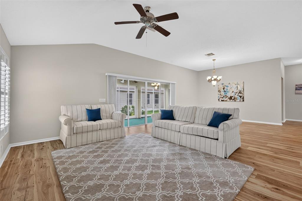 A living room with striped sofas, a patterned rug, wood-look flooring, and a ceiling fan — 17101 SE 94TH BERRIEN COURT, THE VILLAGES, FL