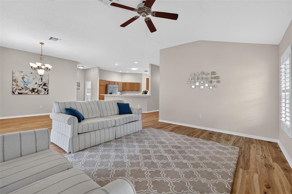 A living room features a striped sofa, a patterned area rug, and wood-look flooring — 17101 SE 94TH BERRIEN COURT, THE VILLAGES, FL