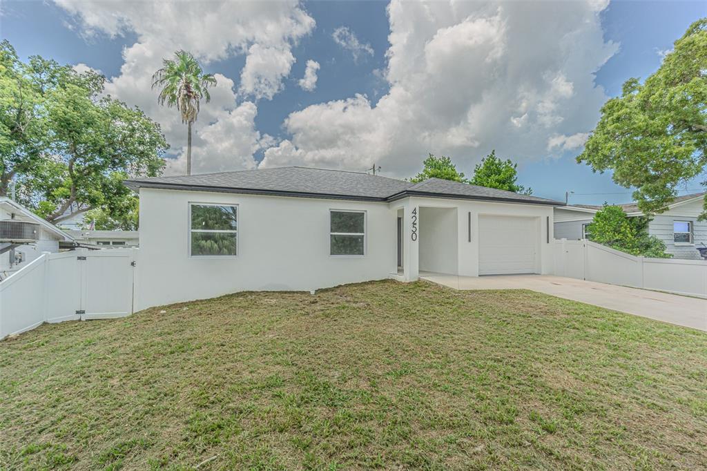 A single-story white house with a garage and a front lawn under a cloudy sky — 4250 OAK BLUFF AVENUE, HOLIDAY, FL