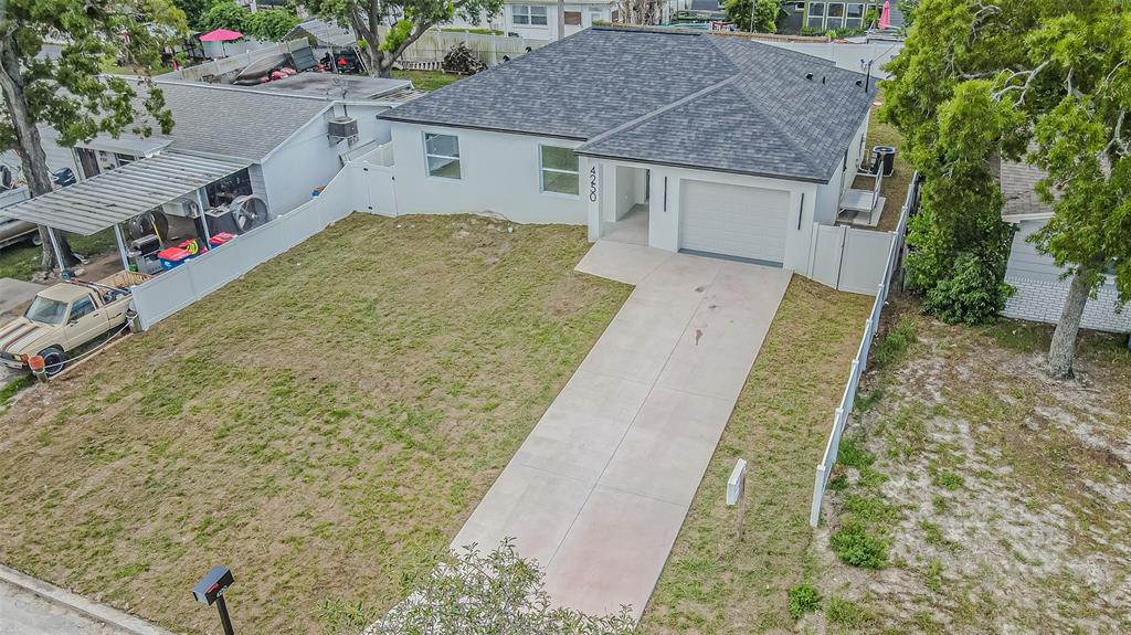 An aerial view shows a single-story house with a white exterior, gray roof, and driveway — 4250 OAK BLUFF AVENUE, HOLIDAY, FL