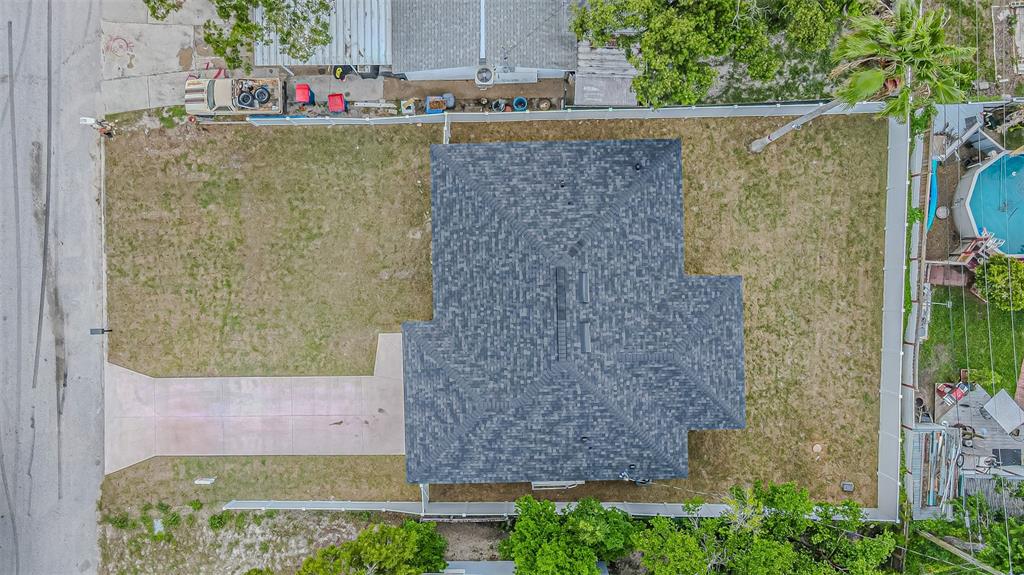 An aerial view shows a house with a dark shingled roof, driveway, and fenced yard — 4250 OAK BLUFF AVENUE, HOLIDAY, FL