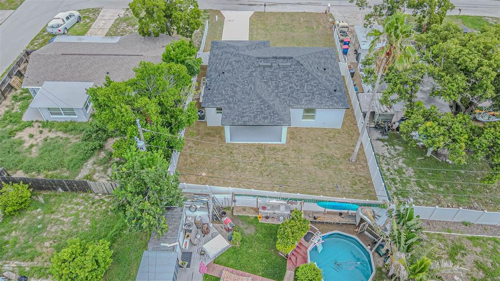 An aerial view shows a house with a dark shingled roof, backyard, and swimming pool — 4250 OAK BLUFF AVENUE, HOLIDAY, FL