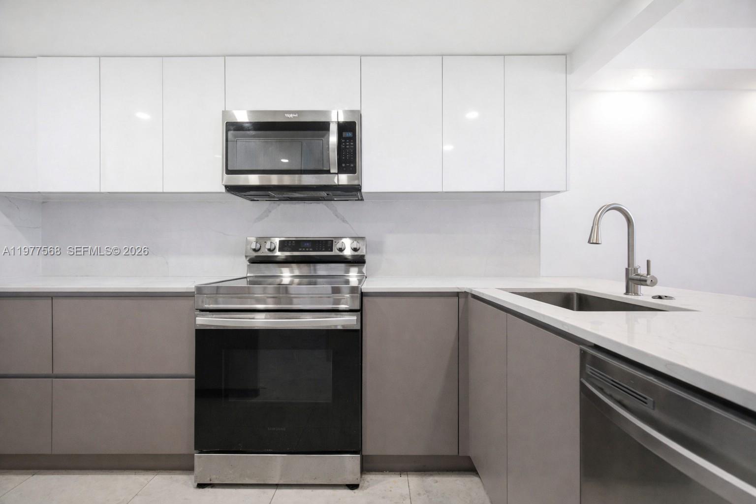 A modern kitchen features white upper cabinets, grey lower cabinets, and stainless steel appliances — 1717 N Bayshore Dr # 3354, Miami FL 33132, MIAMI, FL