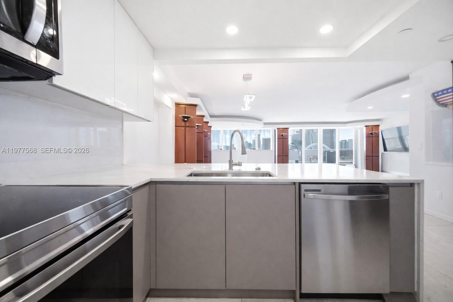 A modern kitchen features white upper cabinets, gray lower cabinets, stainless steel appliances, and city views — 1717 N Bayshore Dr # 3354, Miami FL 33132, MIAMI, FL