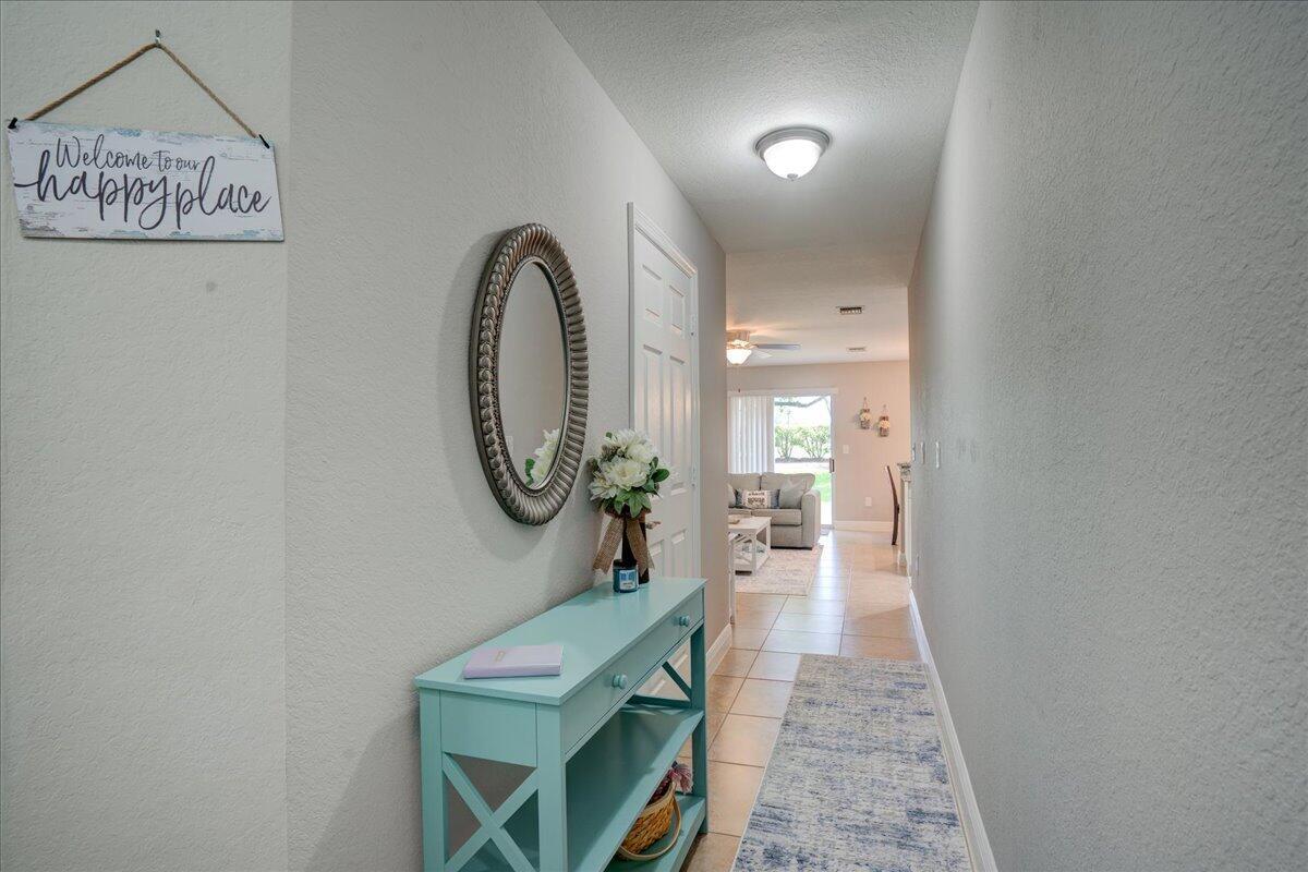 A turquoise console table sits in a hallway with a mirror and a welcome sign — 6633 Old Farm Trail, Boynton Beach FL 33437, BOYNTON BEACH, FL