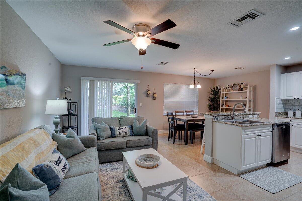 An open-concept living and dining area features a kitchen island, tile flooring, and ceiling fan — 6633 Old Farm Trail, Boynton Beach FL 33437, BOYNTON BEACH, FL