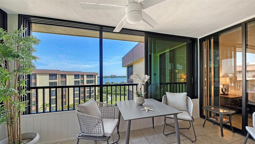 A screened-in balcony features a dining set, a ceiling fan, and views of the water — 8779 MIDNIGHT PASS ROAD UNIT 502H, SARASOTA, FL