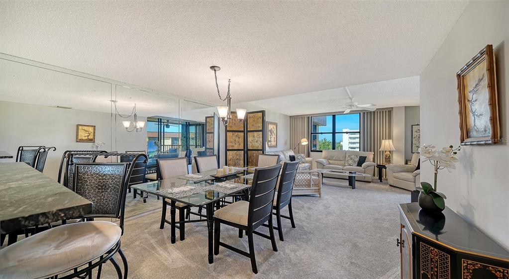 A dining area with a glass table and chairs opens into a carpeted living room — 8779 MIDNIGHT PASS ROAD UNIT 502H, SARASOTA, FL