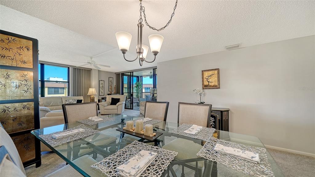 A dining room with a glass table, upholstered chairs, and a view of a balcony — 8779 MIDNIGHT PASS ROAD UNIT 502H, SARASOTA, FL