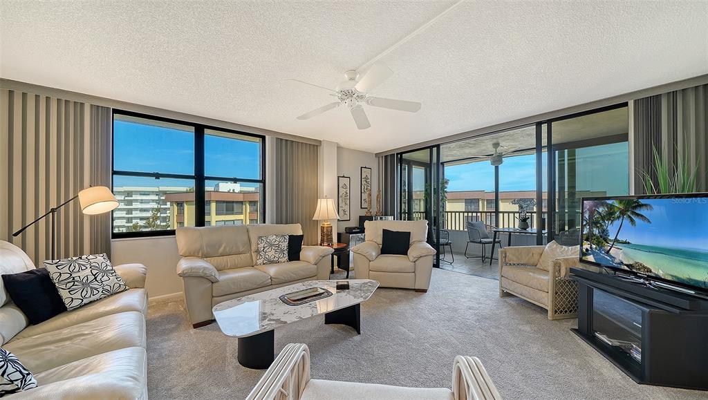A living room features light-colored leather furniture, a marble-topped coffee table, and large sliding glass doors — 8779 MIDNIGHT PASS ROAD UNIT 502H, SARASOTA, FL