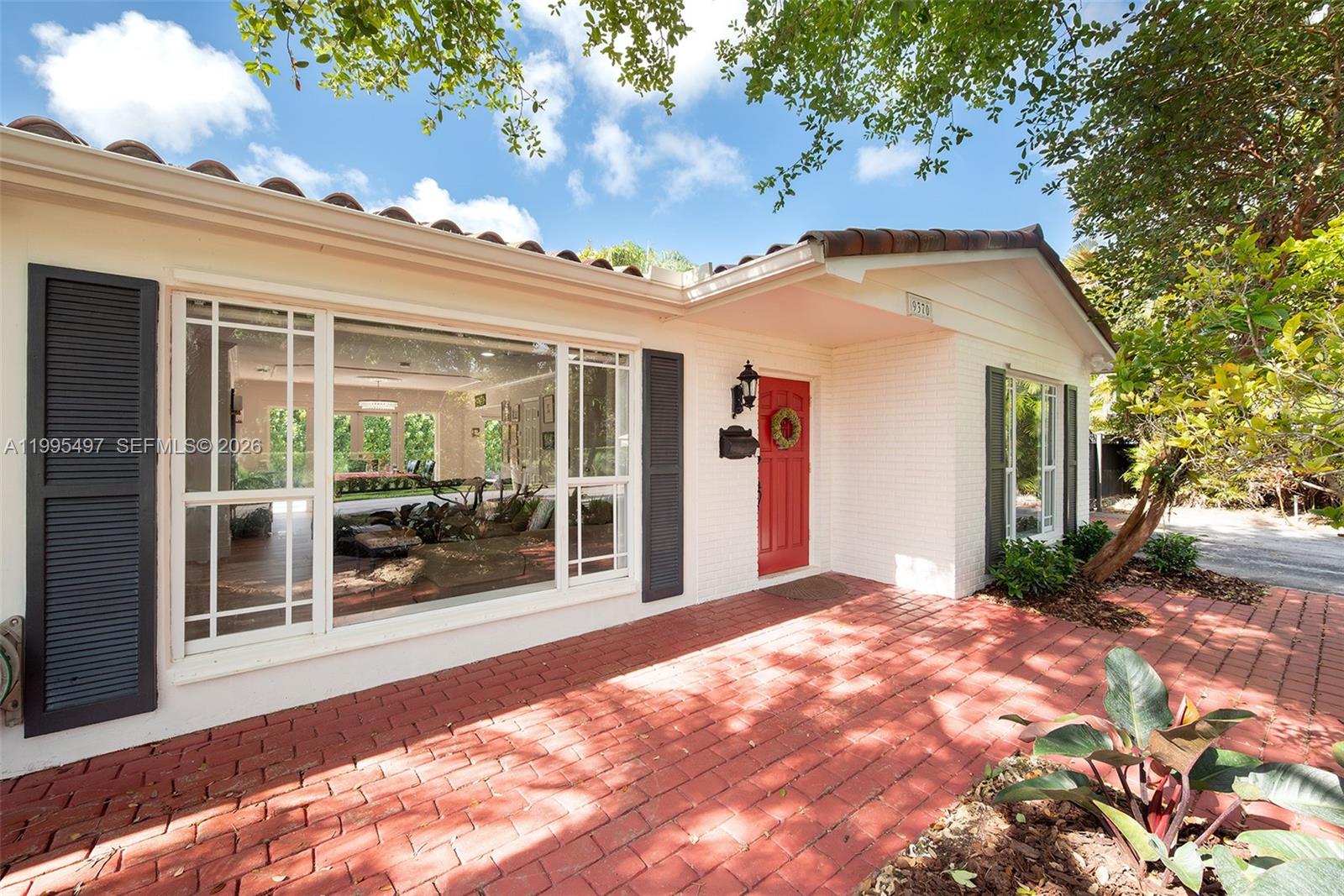 A white brick house features a red front door, dark shutters, and a red brick patio — 9370 SW 82nd St, Miami FL 33173, MIAMI, FL