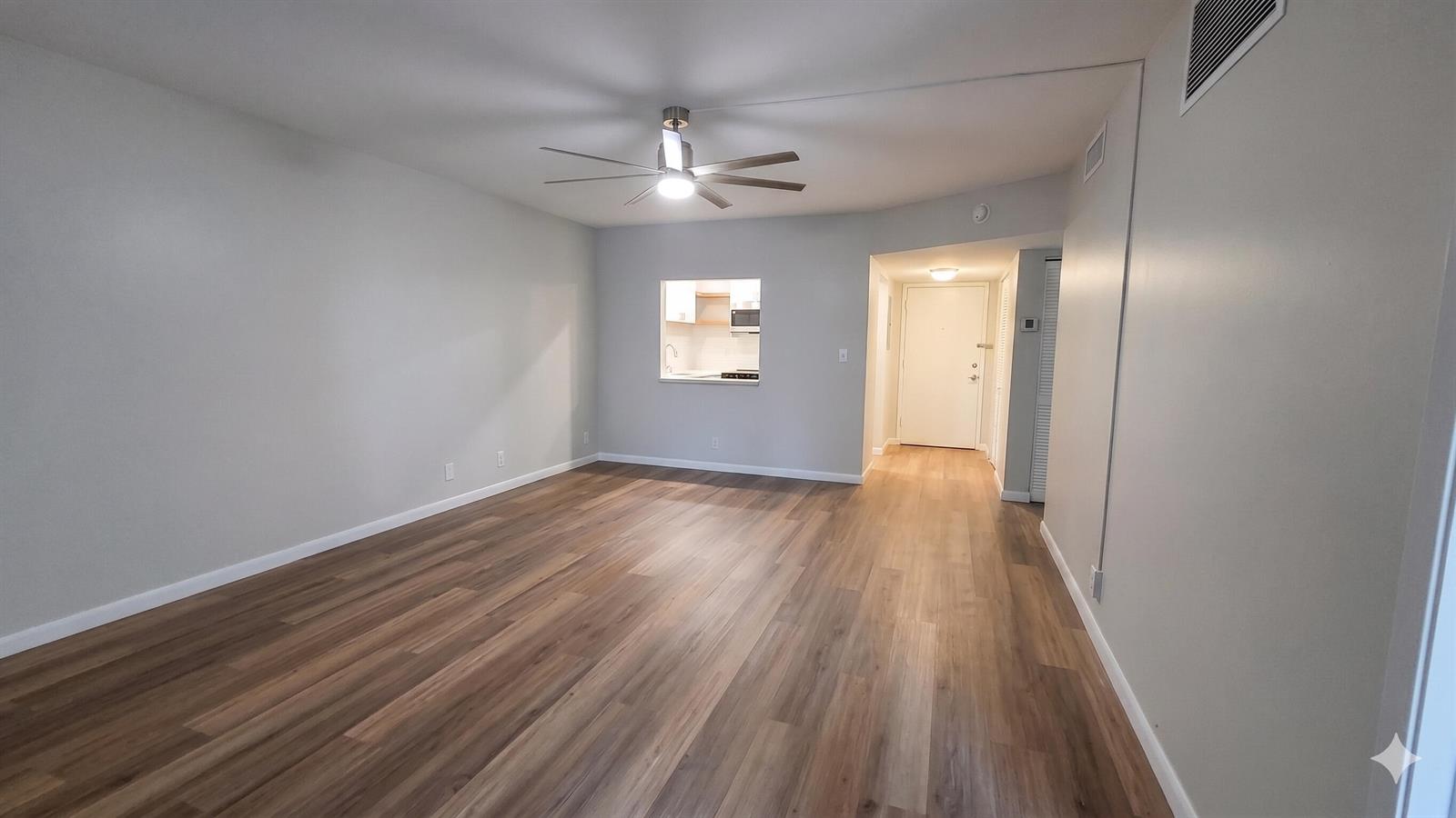 An empty living room features light gray walls, wood-look flooring, and a ceiling fan — 257 S Cypress Road # 408, Pompano Beach FL 33060, POMPANO BEACH, FL