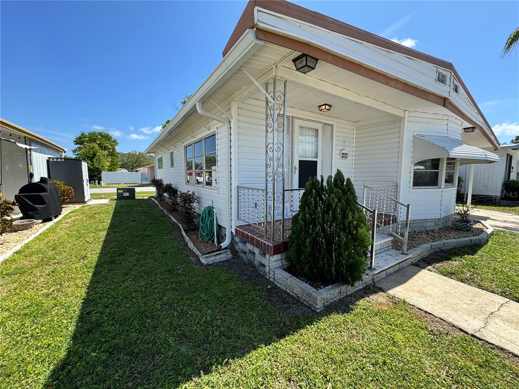 A white mobile home with a small front porch and decorative metal support columns — 2331 BELLEAIR RD Lot 237, CLEARWATER, FL