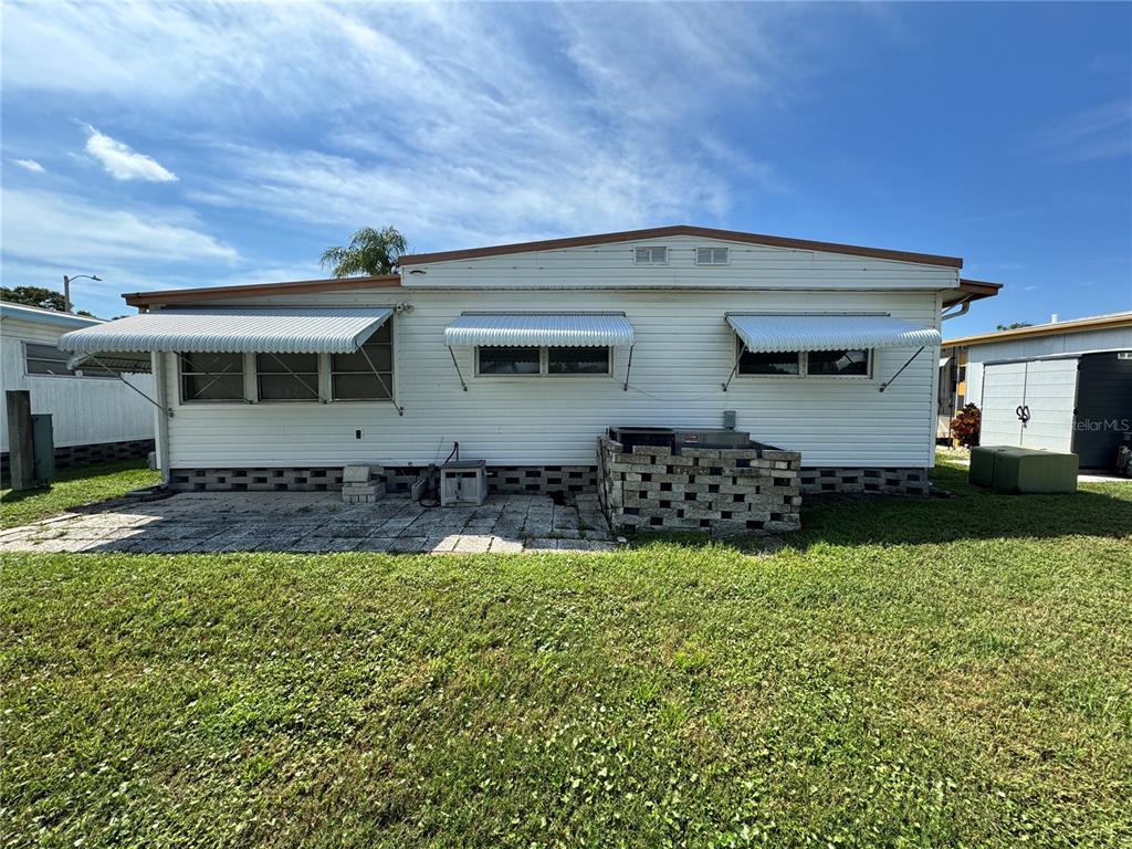 The exterior of a white mobile home features metal awnings over the windows and a patio — 2331 BELLEAIR RD Lot 237, CLEARWATER, FL