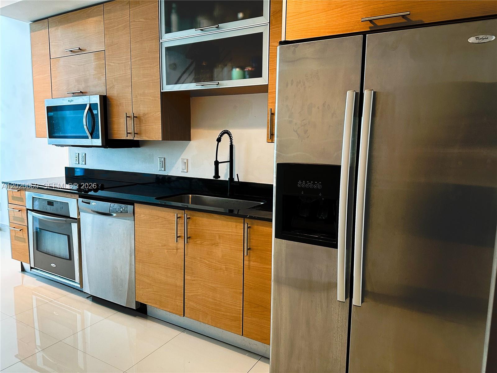 A kitchen features wood cabinets, stainless steel appliances, a black countertop, and a tile floor — 60 SW 13th St # 3418, Miami FL 33130, MIAMI, FL