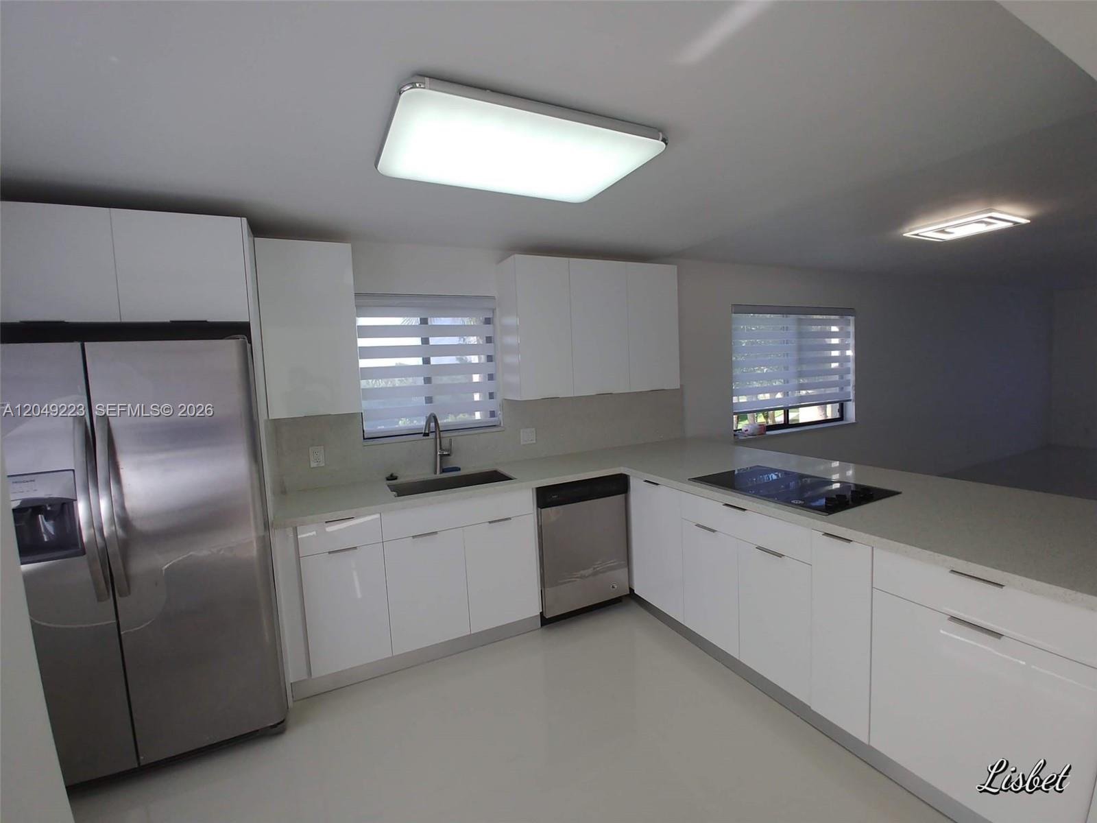 A modern kitchen features white cabinets, stainless steel appliances, and light-colored countertops — WESTON, FL