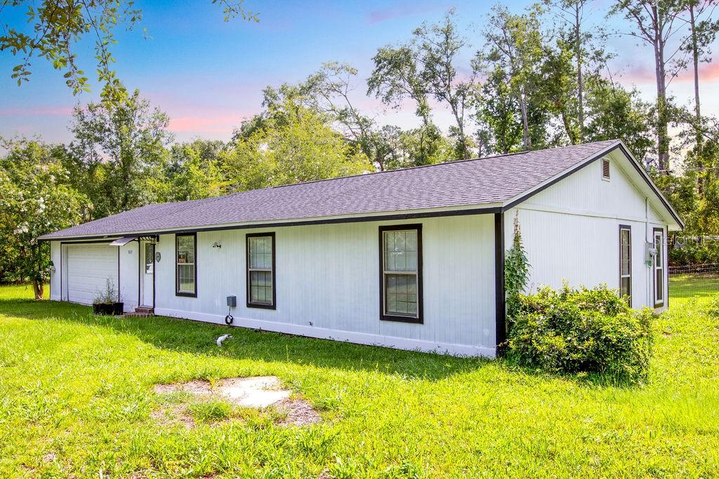 A white single-story house with a dark roof and black window trim sits on grass — 369 NE DIANA TERRACE, LAKE CITY, FL