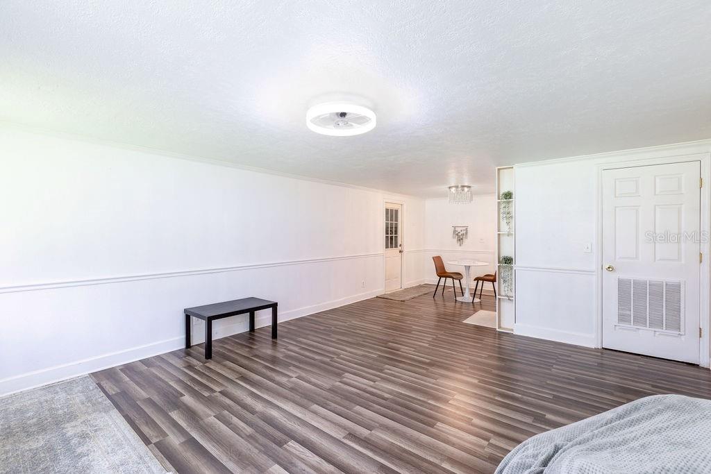 A bright, open-concept room features white walls, chair rail molding, and dark wood-look flooring — 369 NE DIANA TERRACE, LAKE CITY, FL