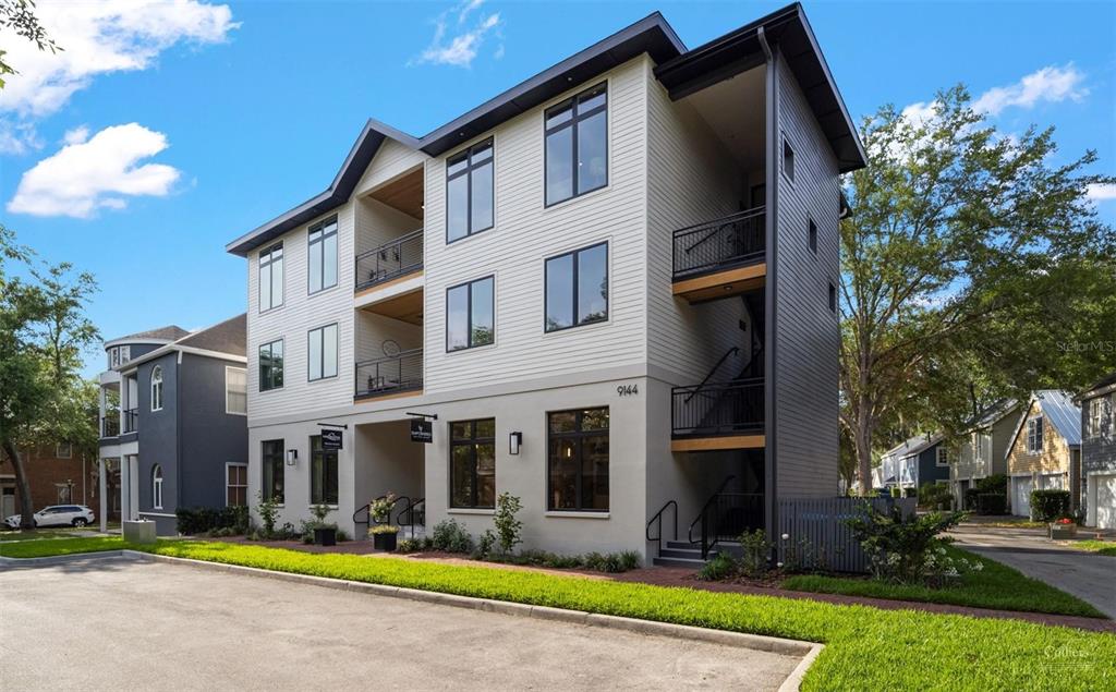 A three-story modern apartment building with light siding, dark trim, and exterior staircases — 9144 SW 49 PLACE UNIT 101, GAINESVILLE, FL