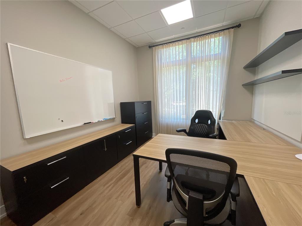 A home office features a desk, two chairs, black storage cabinets, and a large whiteboard — 9144 SW 49 PLACE UNIT 101, GAINESVILLE, FL