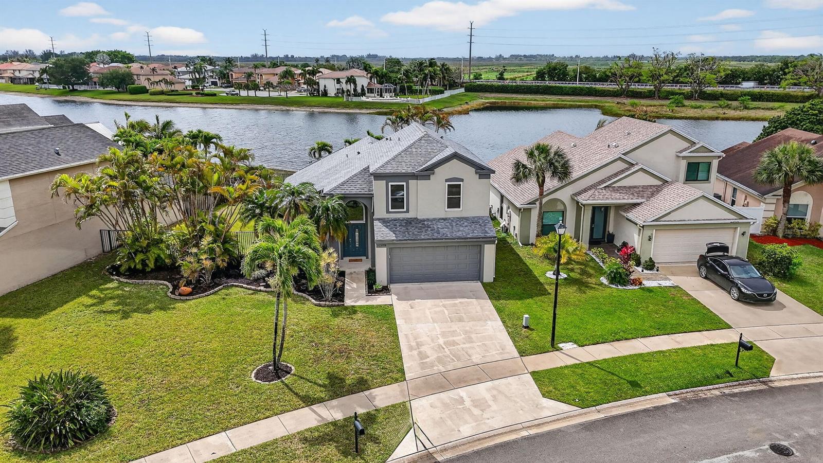 An aerial view shows two suburban houses with driveways, lawns, and palm trees by a lake — 22608 Middletown Drive, Boca Raton FL 33428, BOCA RATON, FL