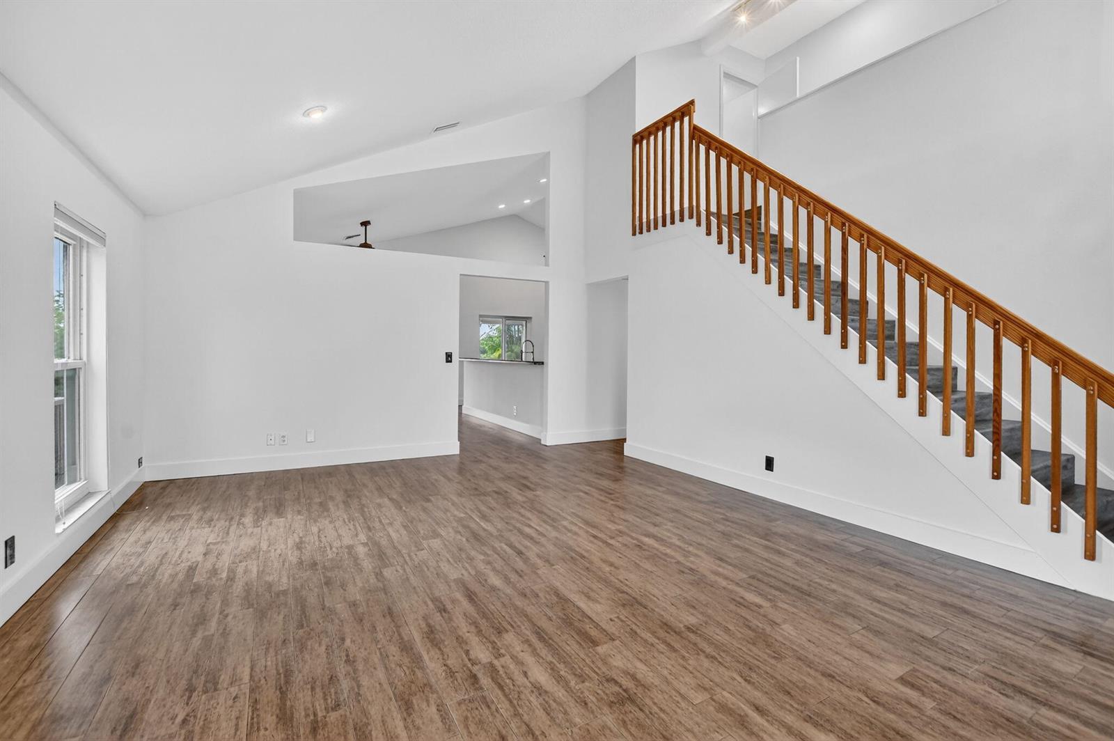 A living room with wood-look flooring, white walls, and a wooden staircase with railings — 22608 Middletown Drive, Boca Raton FL 33428, BOCA RATON, FL