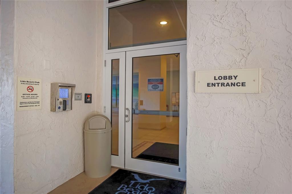 The exterior entrance to the Lido Beach Club lobby features glass doors and signage — 1212 BENJAMIN FRANKLIN DRIVE UNIT 504, SARASOTA, FL