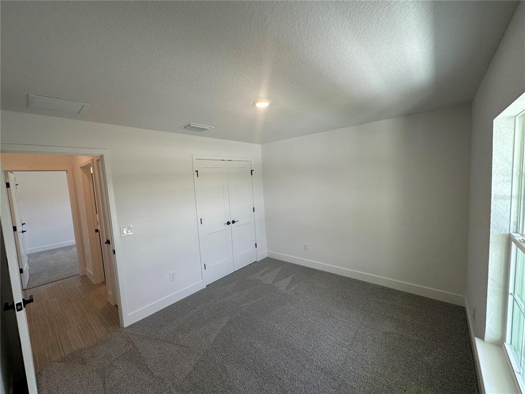 A bedroom with gray carpet, white walls, a closet with double doors, and an open doorway — 12547 NE 48TH TERRACE, OXFORD, FL