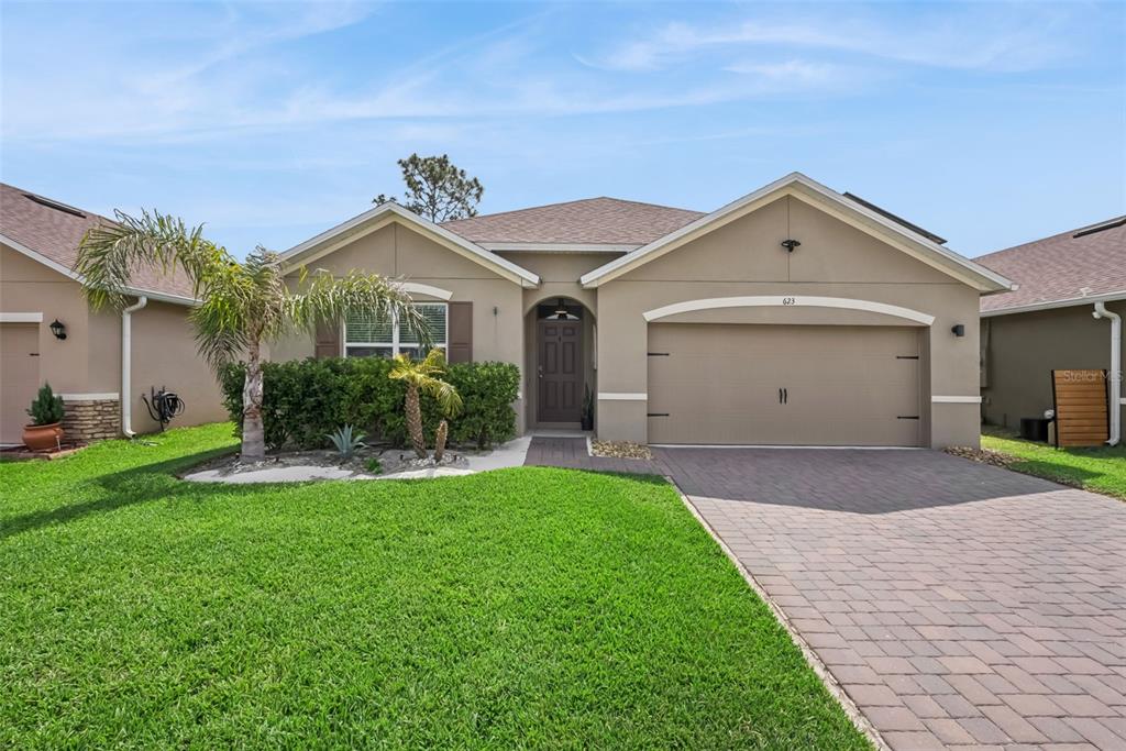 A single-story house with a tan stucco exterior, a paved driveway, and a front lawn — 623 LAZIO CIRCLE, DEBARY, FL