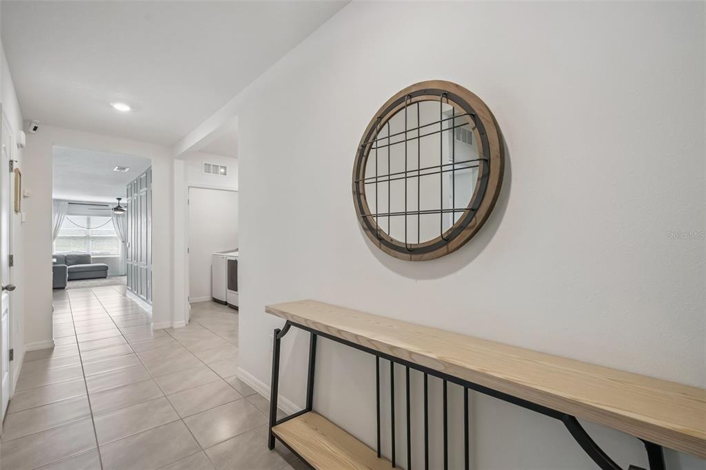 A hallway features light tile flooring, a wooden console table, and a round wall mirror — 623 LAZIO CIRCLE, DEBARY, FL