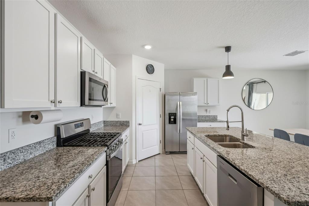 A kitchen features white cabinets, granite countertops, stainless steel appliances, and a central island — 623 LAZIO CIRCLE, DEBARY, FL