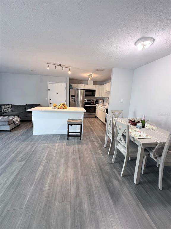 An open-concept kitchen and dining area features white cabinetry, a central island, and gray flooring — 444 BANYON TREE CIRCLE UNIT 202, MAITLAND, FL
