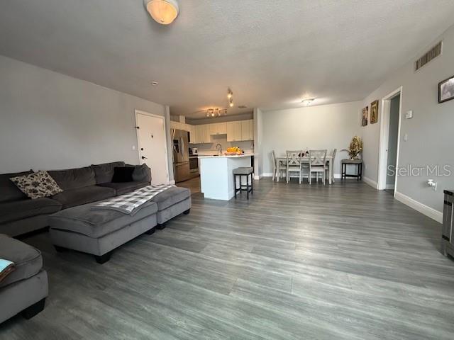 An open-concept living and dining area features gray flooring, a sectional sofa, and kitchen island — 444 BANYON TREE CIRCLE UNIT 202, MAITLAND, FL