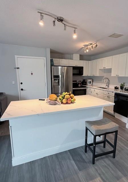 A kitchen features a white quartz island, stainless steel appliances, and white cabinetry — 444 BANYON TREE CIRCLE UNIT 202, MAITLAND, FL