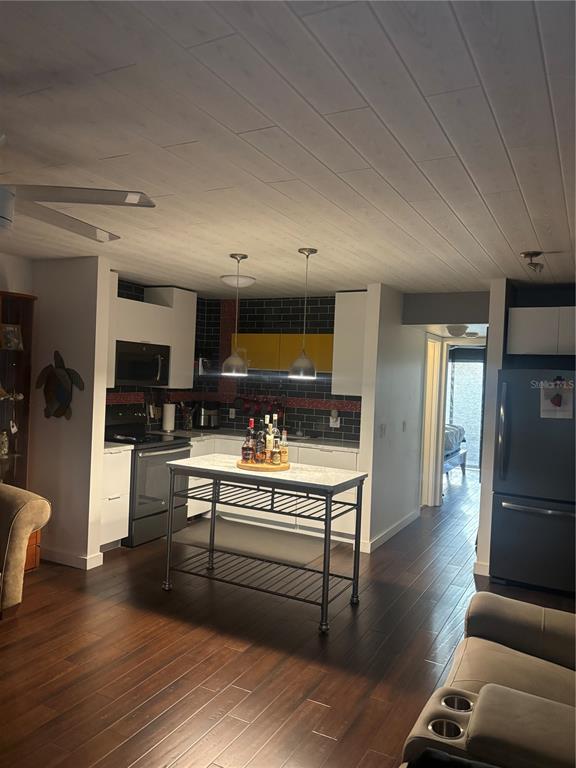 A kitchen features a central island, dark wood flooring, white cabinetry, and a planked ceiling — 133 BERKSHIRE UNIT 133, WEST PALM BEACH, FL