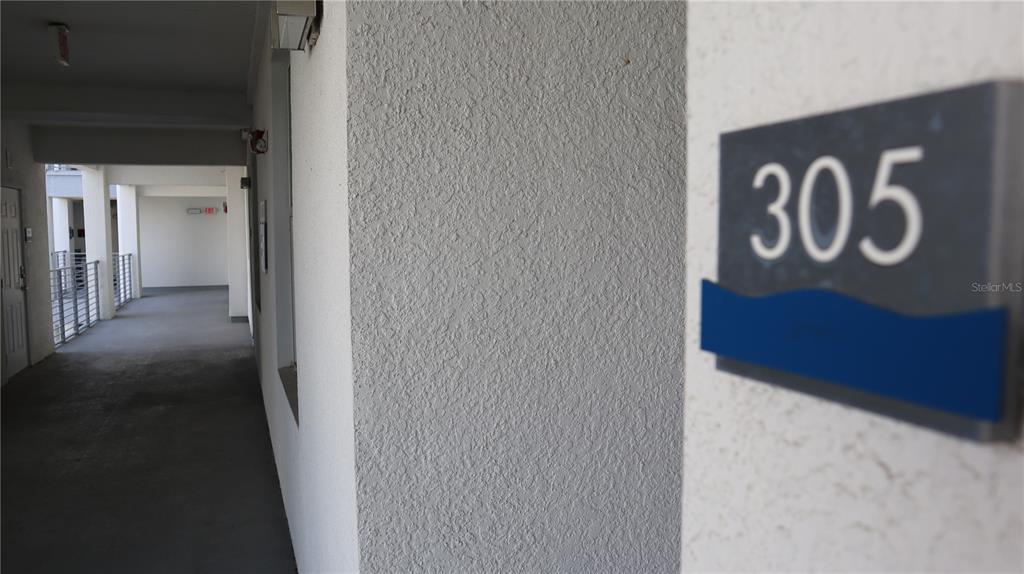 A view of an outdoor apartment hallway with a unit door marked 305 — 4751 CLOCK TOWER DRIVE UNIT 305, KISSIMMEE, FL