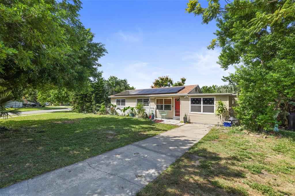 A single-story house with tan siding, a red front door, and solar panels on the roof — 7000 13TH STREET N, ST PETERSBURG, FL