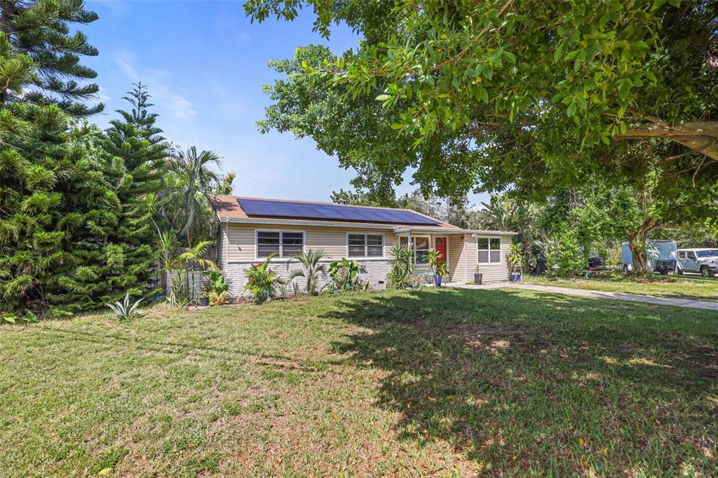 A single-story house with tan siding, a solar panel roof, and a large front lawn — 7000 13TH STREET N, ST PETERSBURG, FL