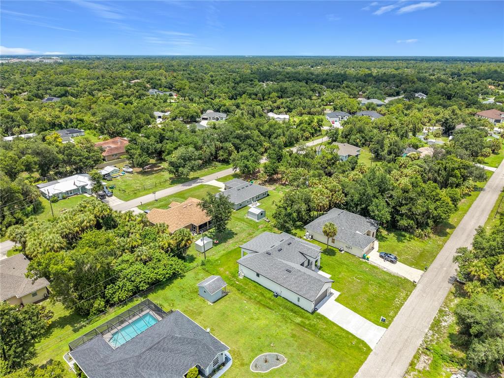An aerial view shows several suburban houses with pools and yards surrounded by dense trees — 275 LECTURN STREET, PORT CHARLOTTE, FL