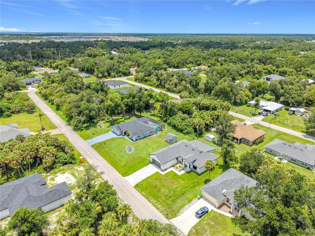 An aerial view shows several single-family homes surrounded by trees and vegetation — 275 LECTURN STREET, PORT CHARLOTTE, FL