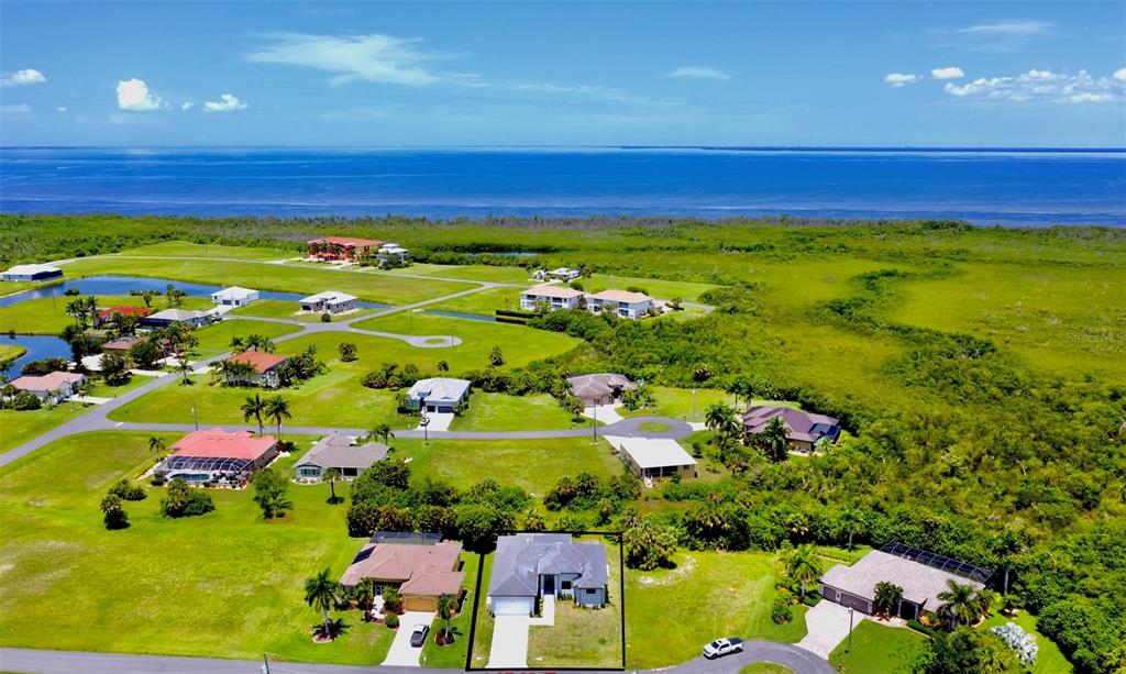 An aerial view shows a residential neighborhood with houses surrounded by green lawns and vegetation — 17425 FUEGO LANE, PUNTA GORDA, FL