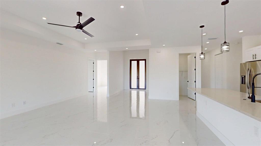A bright, open-concept living area features white marble-look tile floors and a modern ceiling fan — 17425 FUEGO LANE, PUNTA GORDA, FL