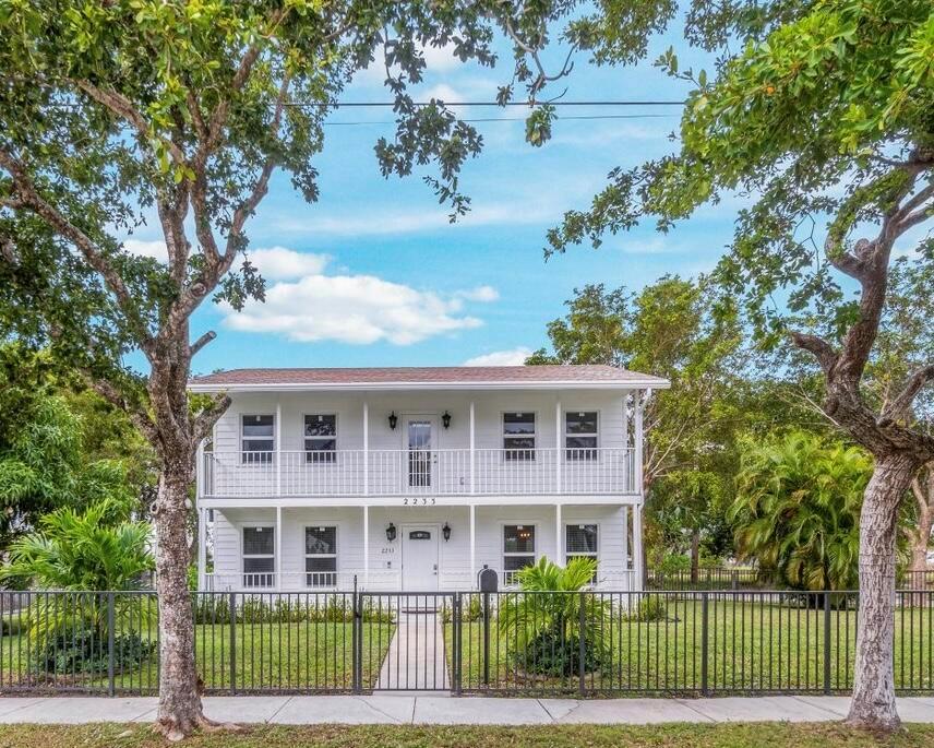 A two-story white house with a balcony and a black metal fence in the front yard — 2233 Dock Street, West Palm Beach FL 33401, WEST PALM BEACH, FL