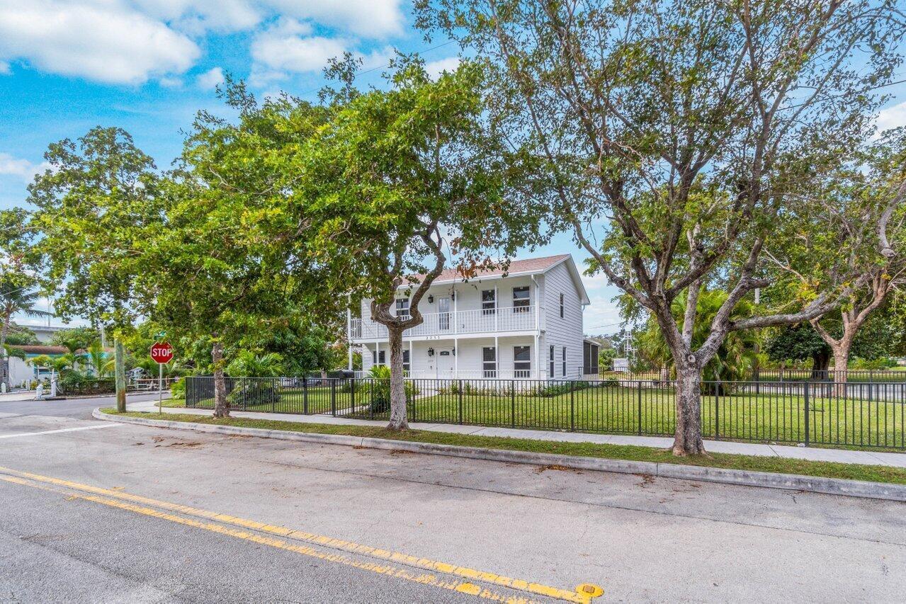 A two-story white house with a balcony stands behind a black metal fence — 2233 Dock Street, West Palm Beach FL 33401, WEST PALM BEACH, FL