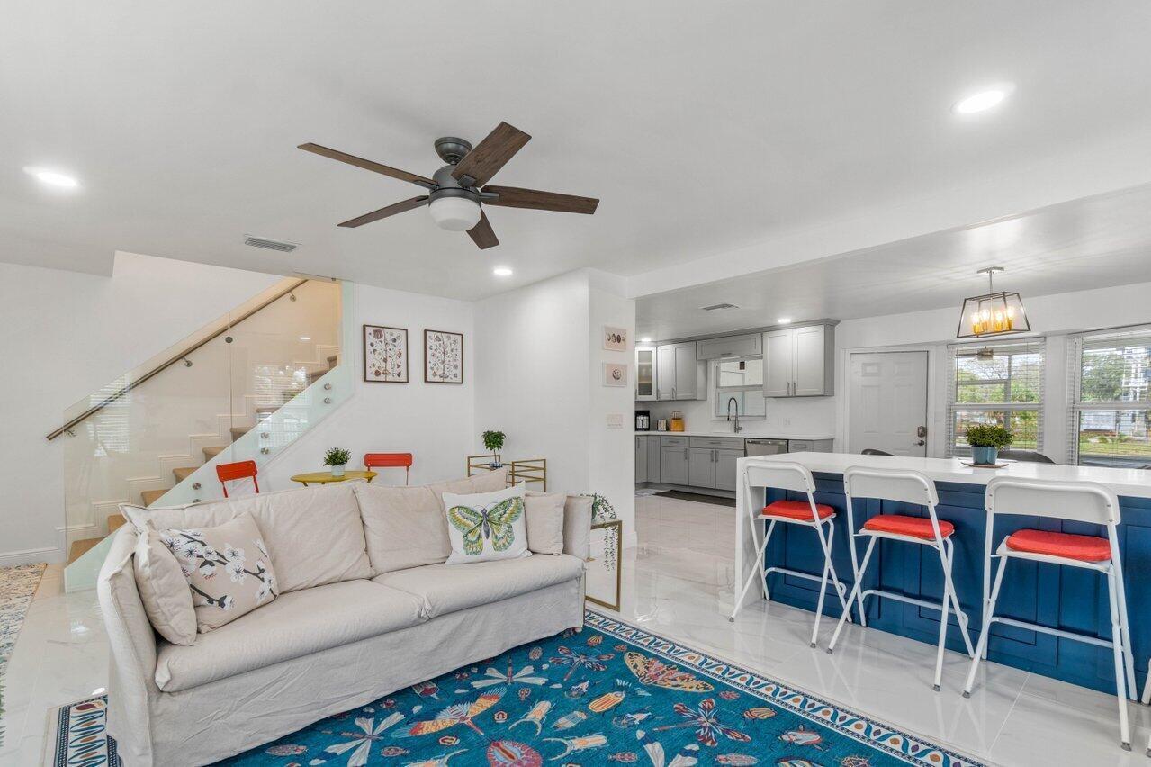 A living room with a blue rug and sofa opens into a kitchen with blue cabinets — 2233 Dock Street, West Palm Beach FL 33401, WEST PALM BEACH, FL