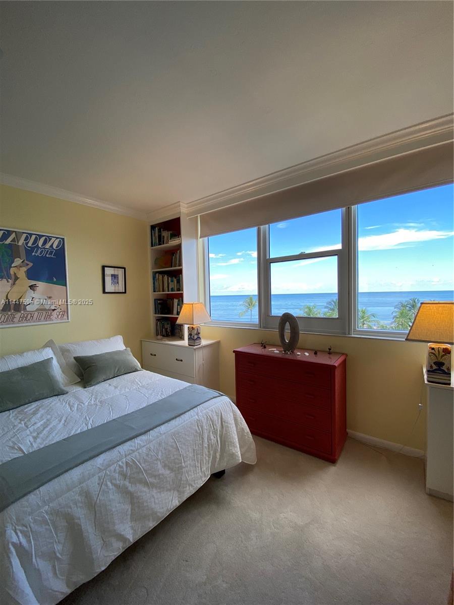 A bedroom with yellow walls, a bed, a red dresser, and an ocean view window — 200 Ocean Lane Dr # 706, Key Biscayne FL 33149, KEY BISCAYNE, FL