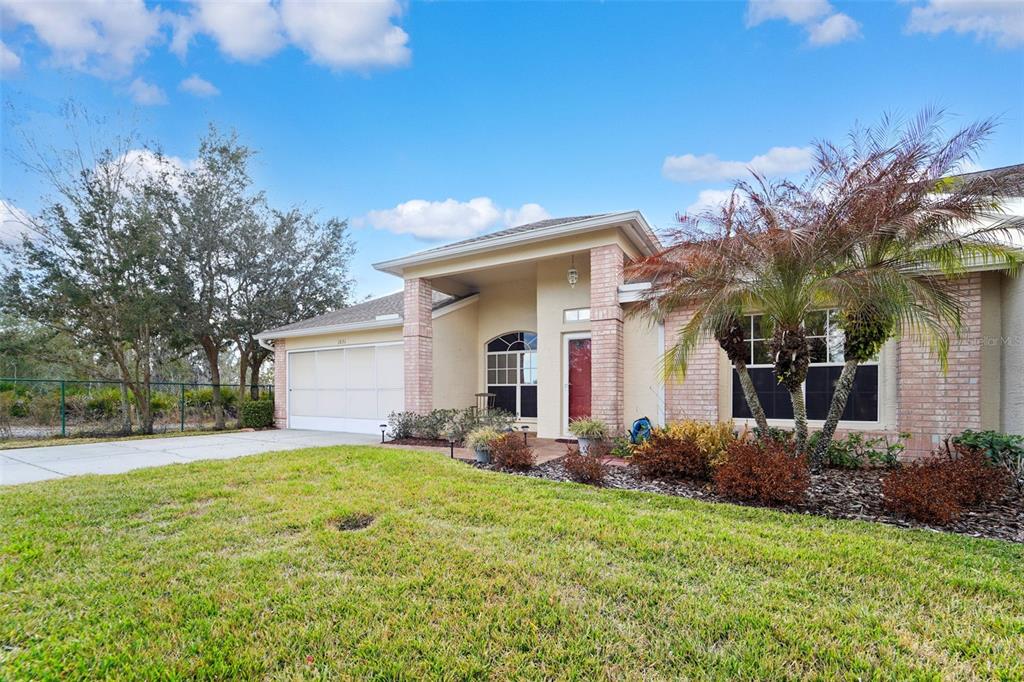 A single-story house with a brick facade, a two-car garage, and a palm tree — 1031 ALMONDWOOD DRIVE, TRINITY, FL