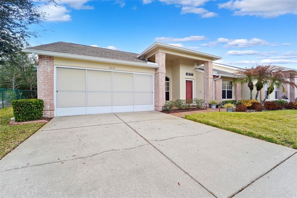 A single-story house with a beige exterior, brick accents, and a concrete driveway — 1031 ALMONDWOOD DRIVE, TRINITY, FL